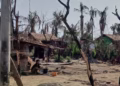 A woman cooks next to destroyed houses and burned trees following fighting between Myanmar's military and the Arakan Army in a village in Minbya Township in Rakhine State on May 21, 2024. FILE PHOTO: AFP